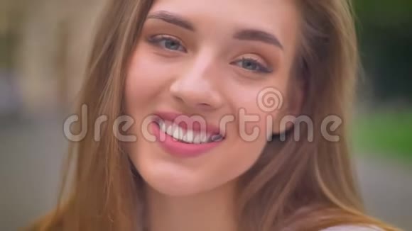 金发美女白种人女性的特写肖像直视镜头和愉快的微笑在外面视频的预览图