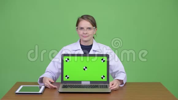 年轻快乐的女医生戴着防护眼镜解释一些笔记本电脑视频的预览图