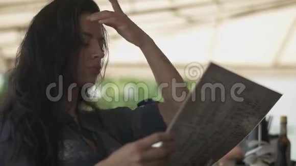 漂亮的女人在餐馆里看菜单纠正她的头发孤独的女孩在咖啡馆里休息视频的预览图