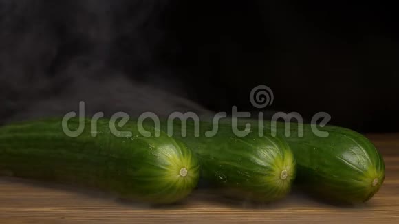 新鲜的旋转蔬菜黑色背景的黄瓜从中蒸发特写缓慢视频的预览图