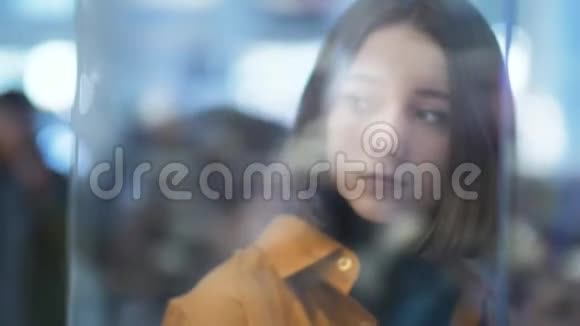玻璃商店里一位年轻漂亮女子的模糊画像眩目的货架聚焦效果人群正在背景中移动视频的预览图
