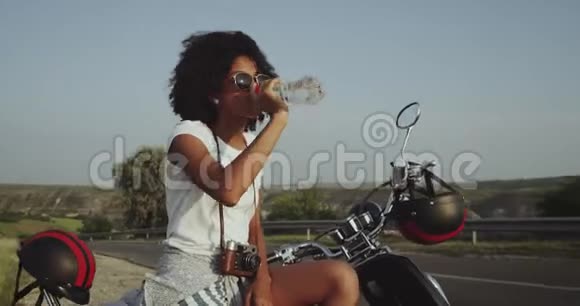 一个拉丁裔卷发女孩渴得要喝水坐在路边的自行车上视频的预览图