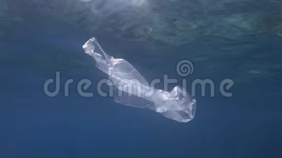 塑料污染蓝色水中透明塑料袋废弃的塑料袋慢慢地漂浮在蓝色的水面下视频的预览图