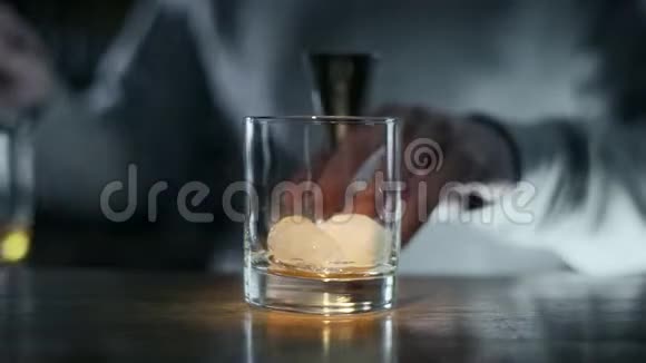 酒保把威士忌倒在酒杯上然后倒在加冰的玻璃杯上在酒吧里调制酒和鸡尾酒视频的预览图