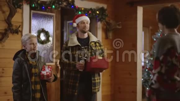 男人和小男孩送给他们的母亲和妻子圣诞礼物和一瓶酒他们拥抱着视频的预览图