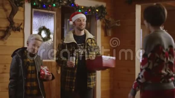 父亲和小儿子把圣诞礼物和一瓶葡萄酒送给女人她吻了男孩视频的预览图