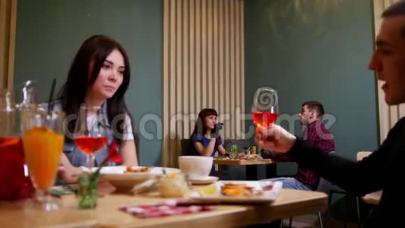 一对年轻夫妇坐在咖啡馆的桌子旁吃喝视频的预览图