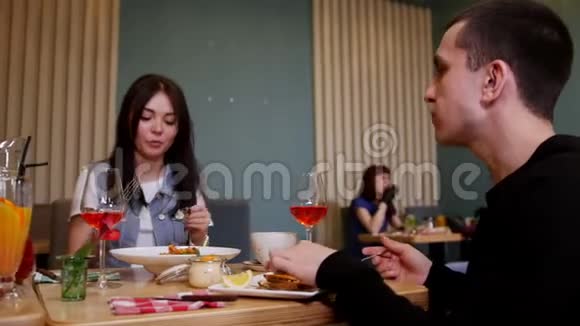 一对年轻夫妇坐在咖啡馆的桌子旁吃海鲜和意大利面视频的预览图