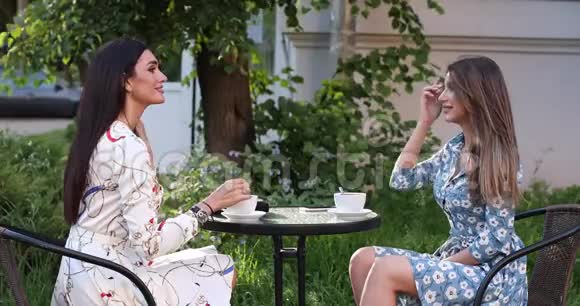两个快乐的女性朋友在户外咖啡馆喝咖啡中长镜头视频的预览图