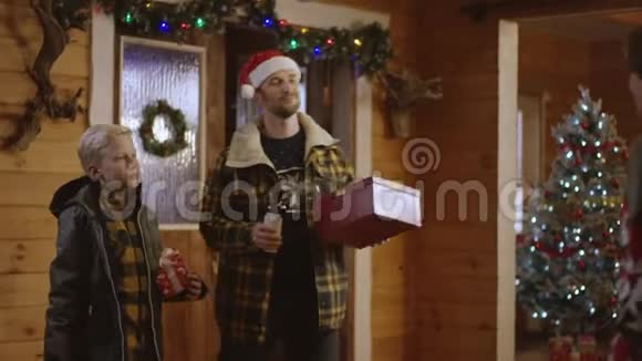父亲和小儿子送给女人圣诞礼物和一瓶酒然后进屋视频的预览图
