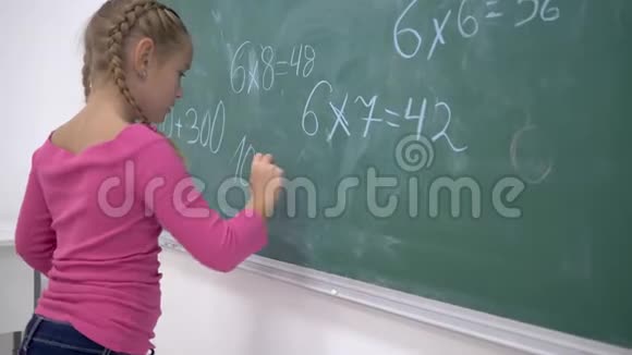 小学教育女生用粉笔在班级绿色黑板上解决数学问题视频的预览图