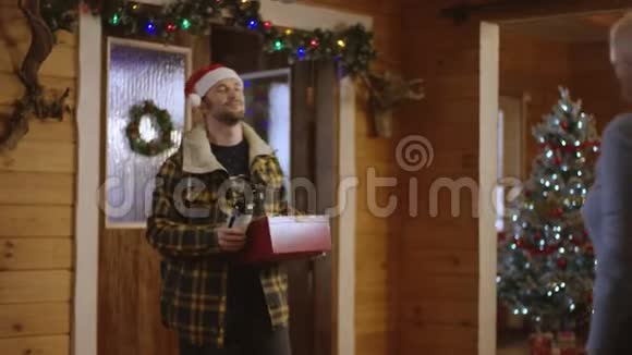 男人给妻子一份圣诞礼物和一个酒瓶她拥抱他让他和她一起进屋视频的预览图
