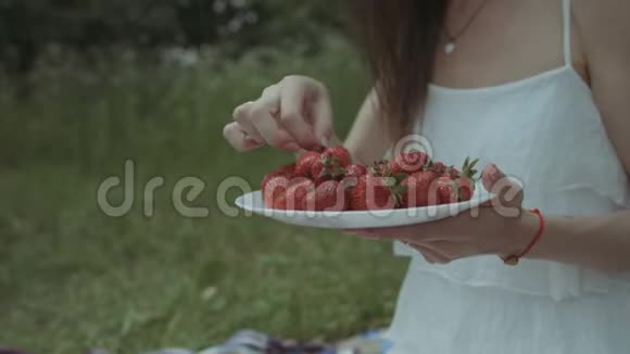 野餐时吃草莓的快乐女人视频的预览图
