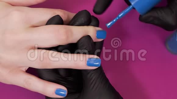摩尼教把客户指甲涂在红色背景上涂上蓝色的指甲油涂上化妆品和指甲然后把指甲贴紧视频的预览图