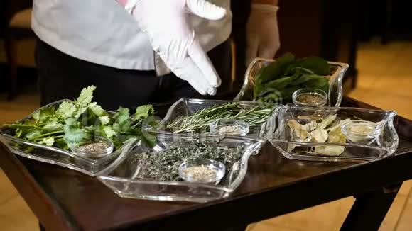专业厨师在各种草药上展示一只戴手套的手用于在地面和新鲜的烹饪透明的健康食品视频的预览图
