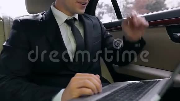 自信的商人坐在有笔记本电脑的车里惊喜的好消息视频的预览图