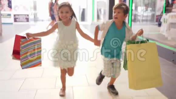 快乐的孩子们带着购物袋在黑色星期五的促销活动中以折扣的方式跑去购物视频的预览图