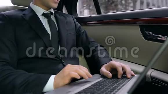 快乐的商人坐在车里用笔记本电脑和微笑成功的交易视频的预览图