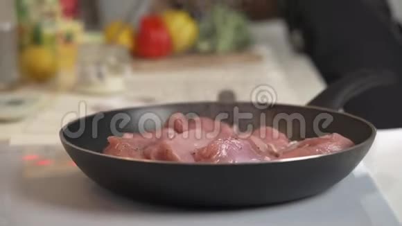 在电炉上煎锅里煎肉女人在电炉上的煎锅里混合炒肉视频的预览图