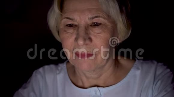 老妇人在家中休息深夜用笔记本电脑阅读新闻只有一张漆黑的脸视频的预览图