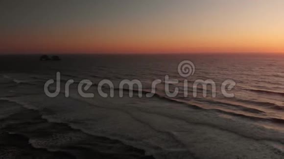 日落时分在俄勒冈州海岸线上的一个长滩上海浪撞击的空中镜头视频的预览图