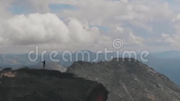 一名男子站在山顶的空中射击年轻的登山者在爬山后高兴地举手视频的预览图
