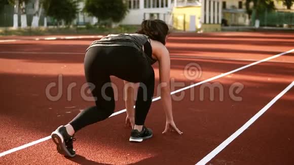 女运动员开始在跑道上跑步穿着黑色紧身裤的运动型黑发女人在跑道上慢跑视频的预览图