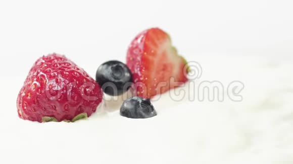 新鲜健康食品蓝莓落在酸奶和鲜奶油与草莓鲜果加鲜奶油视频的预览图
