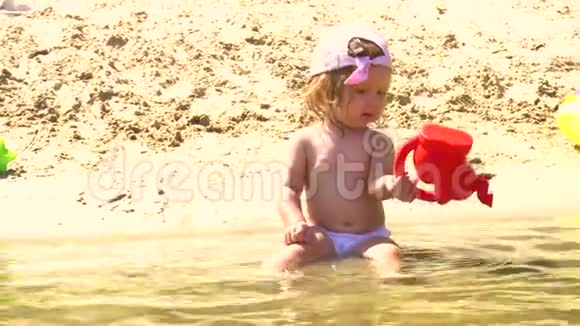沙滩上玩水壶的女婴视频的预览图