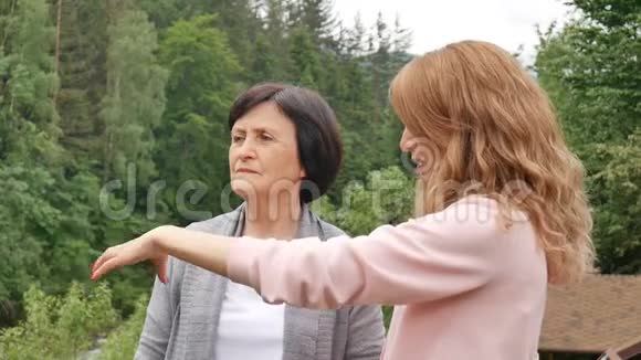 一位年迈的退休母亲和成年女儿正在树林茂密的山脉背景下交谈假期视频的预览图