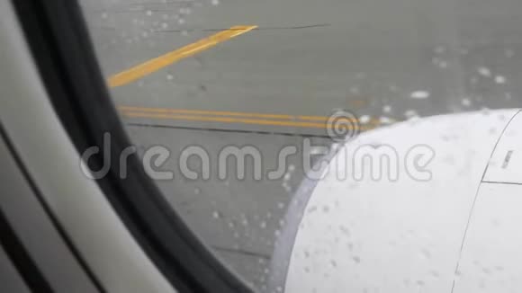 从飞机窗口观看机场跑道和飞机引擎上的雨滴视频的预览图