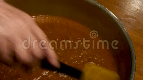 银锅中的红酱用手搅拌视频的预览图