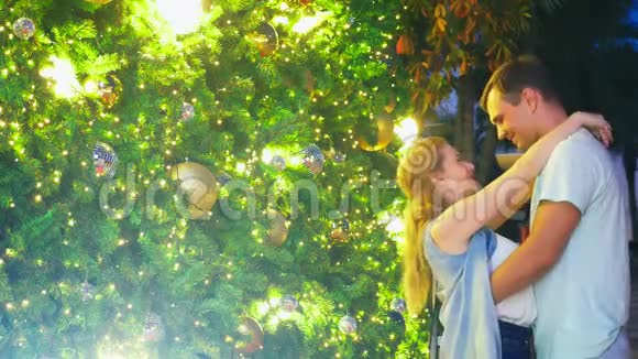 在热带城市圣诞树的背景下快乐的一对夫妇新年相遇恭喜和亲吻这就是视频的预览图