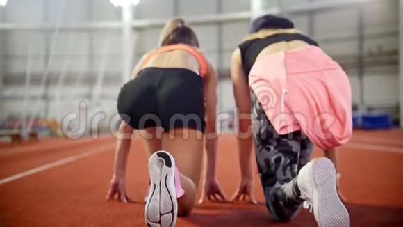 两个年轻的女运动员准备在跑道上跑步开始跑步视频的预览图