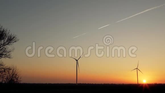 在天空中飞行的飞机的背景下在美丽的日落下风力涡轮机的轮廓视频的预览图