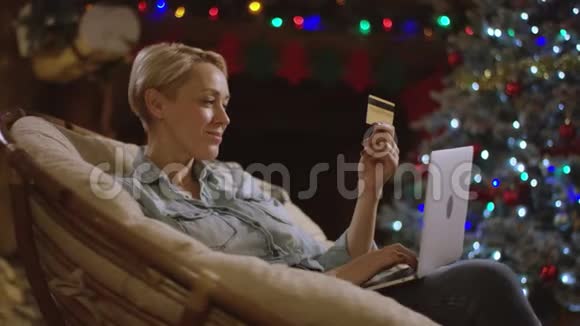 有魅力的女性在圣诞夜使用笔记本电脑和信用卡进行网上购物视频的预览图