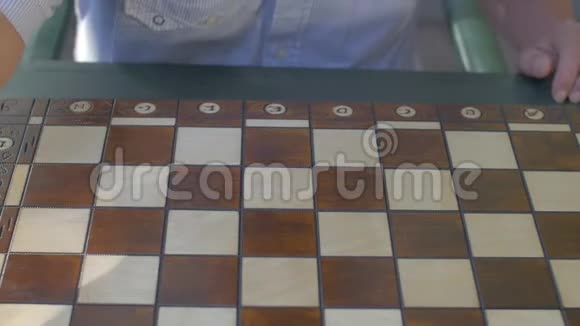 一位白发苍苍的老人在桌旁的花园里准备棋局把白色的数字放在桌上视频的预览图