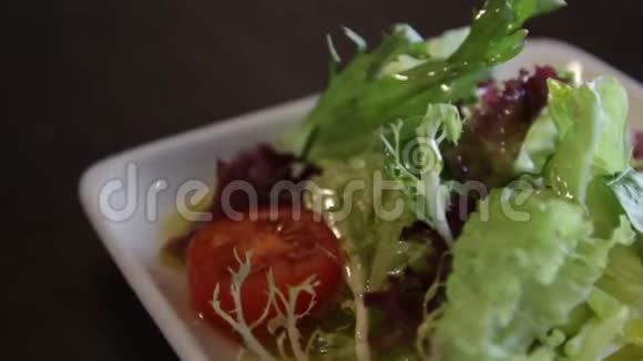 盘子里有绿色生菜西红柿和橄榄油视频的预览图