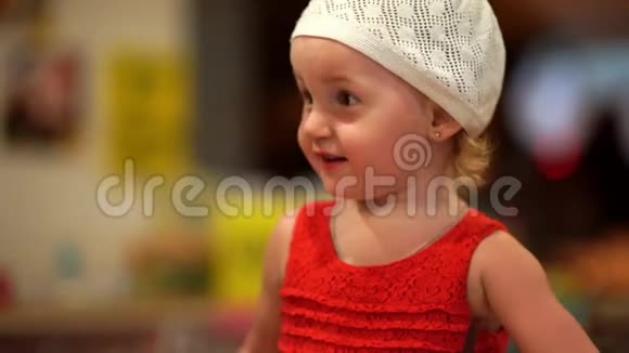 两岁的女孩穿着红色的连衣裙和白色的帽子兴高采烈肖像特写4k视频的预览图