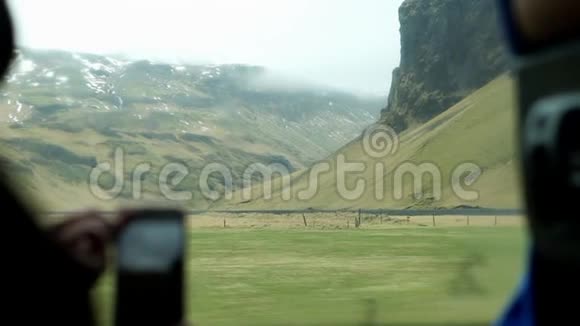 游客从内部巴士通过电话观看冰岛风景视频的预览图
