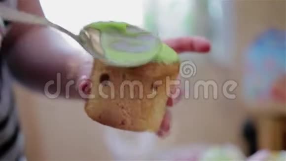 女孩在一个小蛋糕上放了一个甜的绿色釉勺子和蛋糕的特写视频的预览图