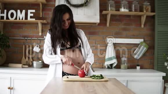美丽的白种人孕妇深色长发在现代的切割板上切割蔬菜装饰视频的预览图