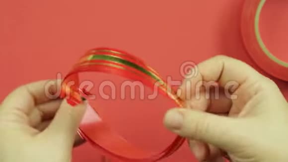 女人双手系着粉红色的辫子粉红色的空白作为礼物蝴蝶结红色背景视频的预览图