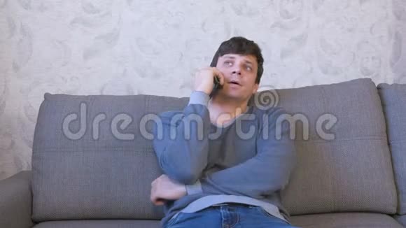 男人在手机上拨一个号码坐在沙发上等待答案视频的预览图