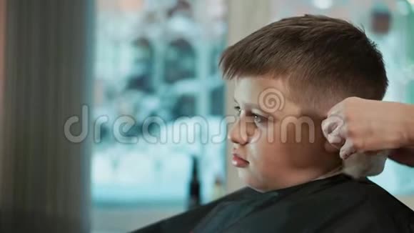 女理发师擦拭男孩脖子上的头发她给他做了个现代发型视频的预览图