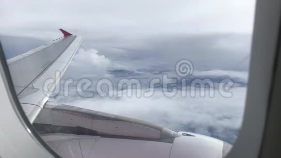 透过飞机窗户观看蓝天和云彩用飞机机翼关闭飞机窗户视频的预览图