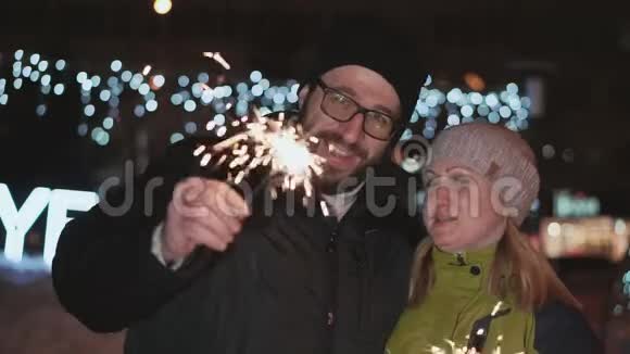 幸福的夫妻夫妻在街上庆祝新年他们手里拿着火花对着视频的预览图
