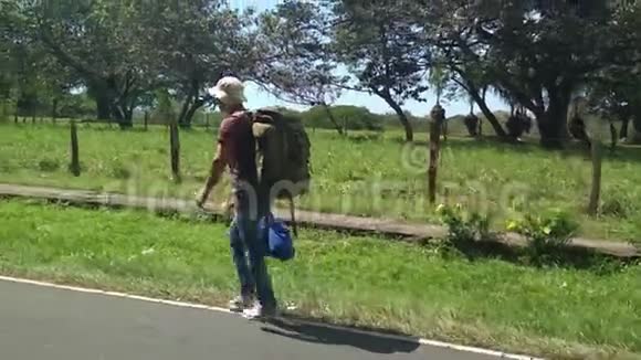 背包旅行者走在美丽的绿色道路上用手机拍摄业余镜头视频的预览图