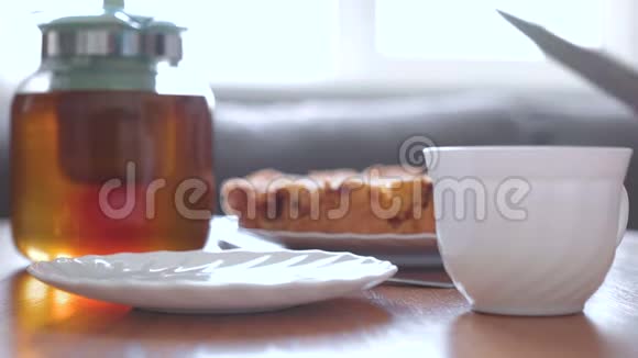 特写女人手把一片自制的苹果派放在碟子上从茶壶里倒一杯茶视频的预览图