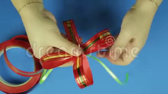 女人手给一个红色丝带蝴蝶结形状蓝色背景视频的预览图